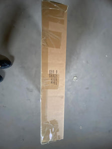 Long cardboard box wrapped in plastic, resting on a concrete floor.